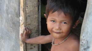 A child in the slums of Pnomh Penh looks out the door of his shack to greet us!